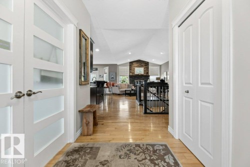 Bright entryway featuring wood-finish flooring, white paneled doors, and a decorative area rug - 5528 43 Street, Lamont, AB 