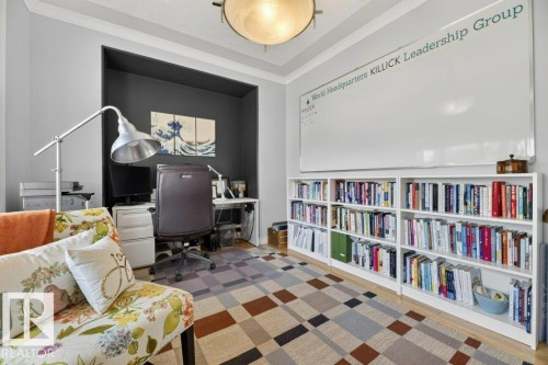 Recessed built-in desk area with dark accent wall, white crown molding, and a ceiling-mounted light fixture - 5528 43 Street, Lamont, AB 