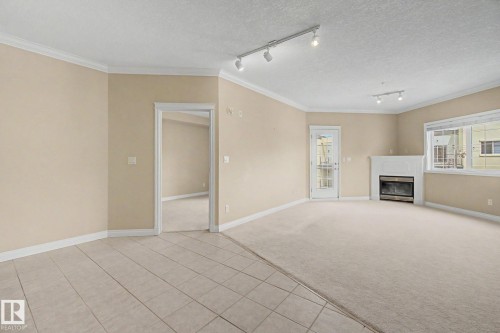 Spacious room with a fireplace, track lighting, and a glass-paneled door - 413 10116 80 Avenue, Edmonton, AB 