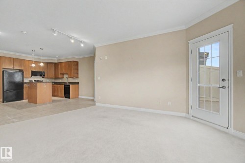 Open-concept living area with light-toned carpeting and neutral wall paint - 413 10116 80 Avenue, Edmonton, AB 