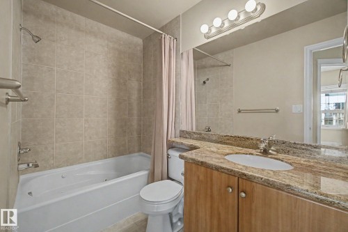 Bathroom featuring a vanity with a light-toned countertop, an undermount sink, and wood-finish cabinetry - 413 10116 80 Avenue, Edmonton, AB 