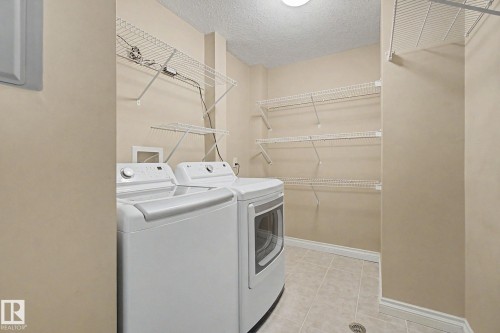 Dedicated laundry area featuring a washer and dryer, tile flooring, and multiple wire shelving units - 413 10116 80 Avenue, Edmonton, AB 