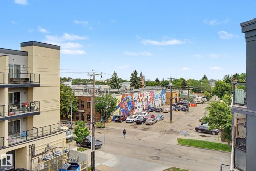 The surrounding streetscape features a multi-story building with multiple balconies, a paved street, and an adjacent parking area - 413 10116 80 Avenue, Edmonton, AB 