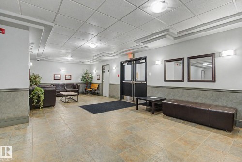 Spacious common area featuring durable tile flooring, recessed and wall-mounted lighting, and a neutral color palette - 413 10116 80 Avenue, Edmonton, AB 