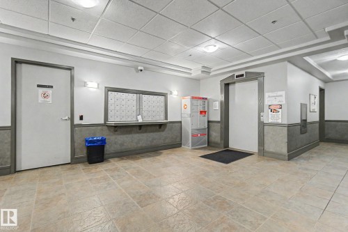 Spacious common area featuring textured tile flooring, recessed lighting, wall sconces, and crown molding - 413 10116 80 Avenue, Edmonton, AB 
