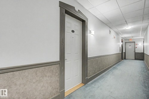 Corridor featuring a textured wall covering, decorative wainscoting, and recessed lighting - 413 10116 80 Avenue, Edmonton, AB 