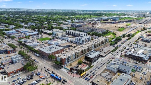 Aerial view showcasing a dynamic urban landscape featuring commercial buildings, multi-story residential structures, and established tree-lined streets - 413 10116 80 Avenue, Edmonton, AB 
