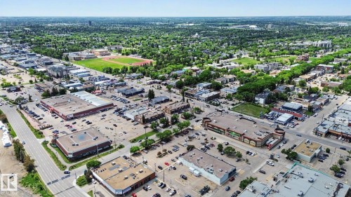Aerial perspective showcasing a commercial district with various retail buildings and expansive parking areas - 413 10116 80 Avenue, Edmonton, AB 