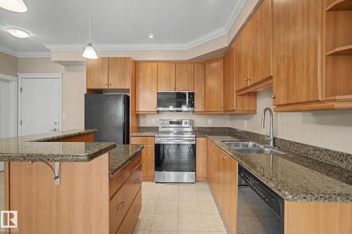 Kitchen featuring light wood cabinetry, granite countertops, and stainless steel appliances - 413 10116 80 Avenue, Edmonton, AB 