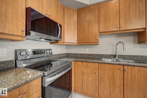 Kitchen featuring wood-finish cabinetry and granite countertops - 413 10116 80 Avenue, Edmonton, AB 