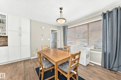 Dining area featuring wood-finish flooring, a contemporary ceiling light fixture, and white built-in cabinetry with both solid and glass-front doors - 