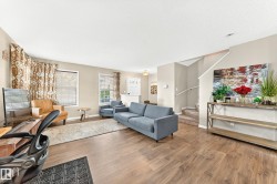 Spacious living area featuring wood-finish flooring, neutral wall tones, and multiple windows - 