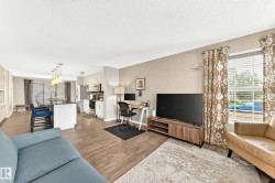 Open-concept living area with wood-finish flooring, a kitchen island, and a dedicated workspace - 