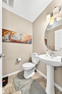 Powder room featuring a pedestal sink, round mirror, and tile flooring - 