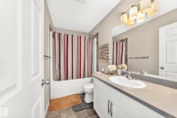 Full bathroom featuring a white vanity with a single basin sink and a neutral-toned countertop - 