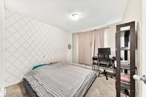 Carpeted bedroom featuring patterned accent wall, neutral wall paint, and a window with curtains - 875 Chappelle Link Link, Edmonton, AB 