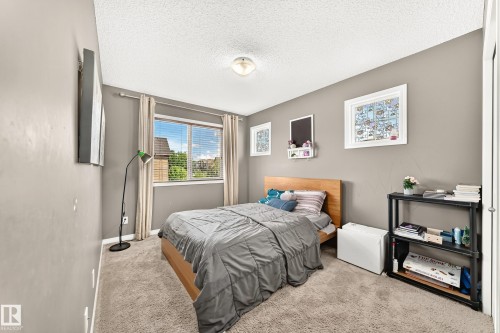 Carpeted bedroom with a single window featuring horizontal blinds and light-colored drapes - 875 Chappelle Link Link, Edmonton, AB 