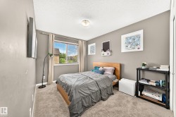 Carpeted bedroom with a single window featuring horizontal blinds and light-colored drapes - 