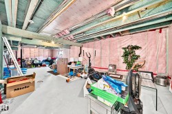 Unfinished basement with exposed ceiling joists, concrete flooring, and insulated walls - 