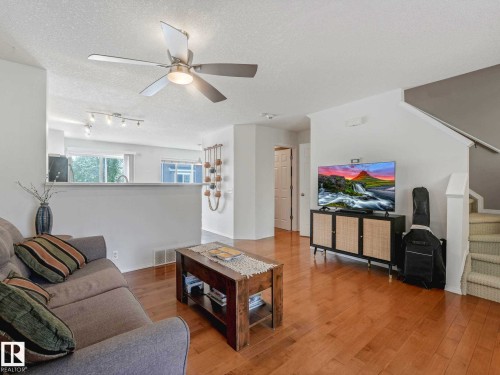 Hardwood-finish flooring extending through the living area, featuring a ceiling fan with integrated lighting - 62 3075 Trelle Crescent Nw, Edmonton, AB - Indoor Photo Showing Living Room