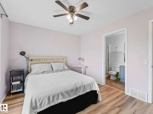 Room featuring wood-finish flooring, a ceiling fan with integrated lighting, and direct access to a bathroom - 62 3075 Trelle Crescent Nw, Edmonton, AB - Indoor Photo Showing Bedroom