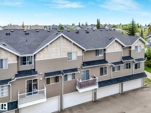 Multi-level townhome exterior featuring neutral-toned siding, gabled roofs with dark shingles, individual balconies with white railings, multiple windows, and integrated garage doors - 62 3075 Trelle Crescent Nw, Edmonton, AB - Outdoor