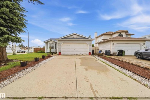 Front exterior featuring light-toned siding, a two-car garage, and an extended driveway - 4428 11A Avenue, Edmonton, AB 