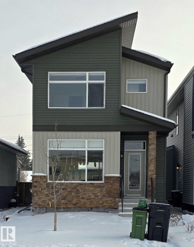 Contemporary exterior featuring a split-level roofline, multi-toned siding, stone accent base, large windows, and a covered entry - #Basement 10923 159 St Nw, Edmonton, AB - Outdoor With Exterior