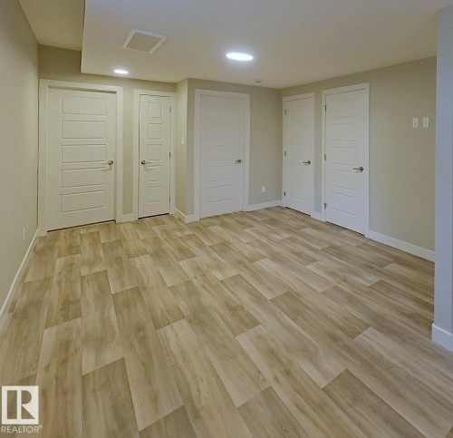 Spacious room featuring wood-finish flooring, recessed lighting, and multiple panel doors with contemporary hardware - #Basement 10923 159 St Nw, Edmonton, AB - Indoor Photo Showing Other Room