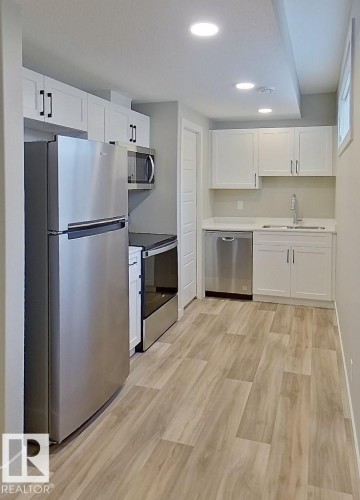 Kitchenette featuring stainless steel appliances, white cabinetry with dark hardware, a white countertop, recessed lighting, and wood-finish flooring - #Basement 10923 159 St Nw, Edmonton, AB - Indoor Photo Showing Kitchen With Stainless Steel Kitchen