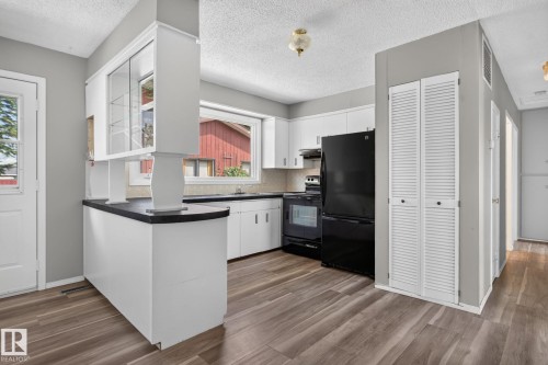 Well-appointed kitchen featuring white cabinetry, dark countertops, and wood-finish flooring - 13431 109 Street, Edmonton, AB 