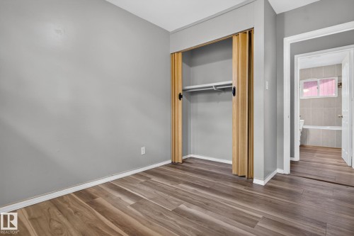 Room featuring wood-finish flooring, light grey painted walls, and white baseboards - 13431 109 Street, Edmonton, AB 