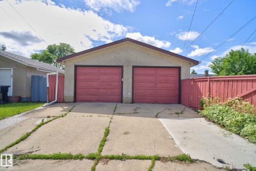 Detached two-car garage with red panel doors, stucco exterior, and a brown trim roofline - 13431 109 Street, Edmonton, AB 