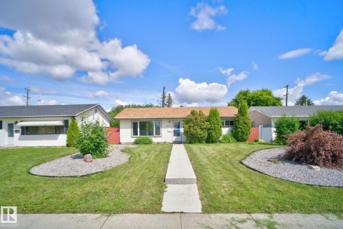 Exterior featuring a light-colored facade, a brown shingle roof, and a central sidewalk - 13431 109 Street, Edmonton, AB 