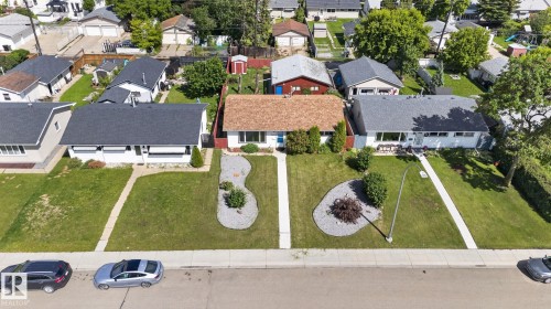Property with a prominent front yard featuring a concrete walkway, two distinct landscaped rock gardens with plantings, and a mature tree - 13431 109 Street, Edmonton, AB 