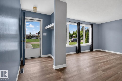 Wood-finish flooring throughout, featuring a bright entry with a full-light door and a built-in shelving unit - 13431 109 Street, Edmonton, AB 