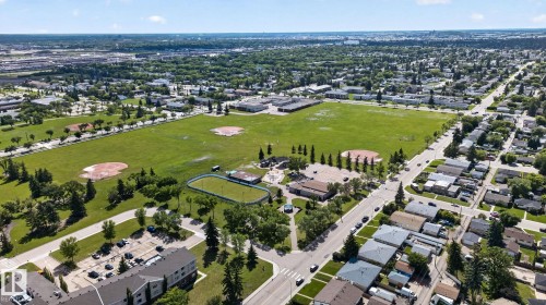 Expansive green space featuring multiple baseball diamonds, a track, and mature trees, surrounded by residential streets and urban landscaping - 13431 109 Street, Edmonton, AB 