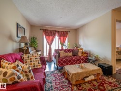 Living room featuring dark wood-finish flooring, neutral-toned walls, a window with decorative drapes, and a doorway leading to another room - 
