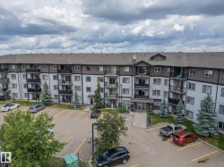 Multi-story residential building featuring balconies, a covered main entrance, and a surrounding parking area - 
