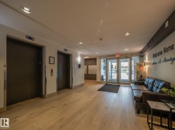 Main lobby featuring light wood-finish flooring, recessed lighting, and dual elevator access - 