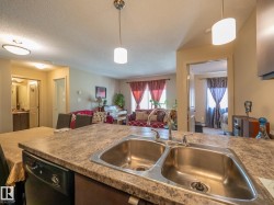 Kitchen featuring a double stainless steel sink with chrome faucet, laminate countertops, and a built-in dishwasher - 