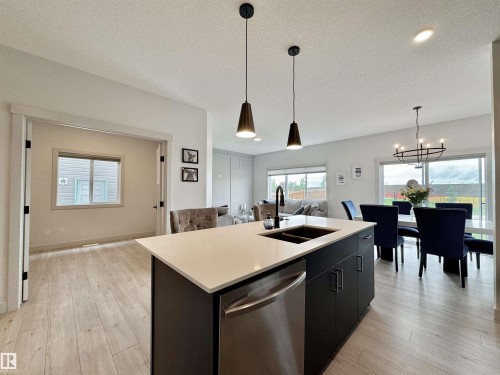 Kitchen island featuring a white countertop, undermount sink, and stainless steel dishwasher - 33 Sumac Close, Fort Saskatchewan, AB 