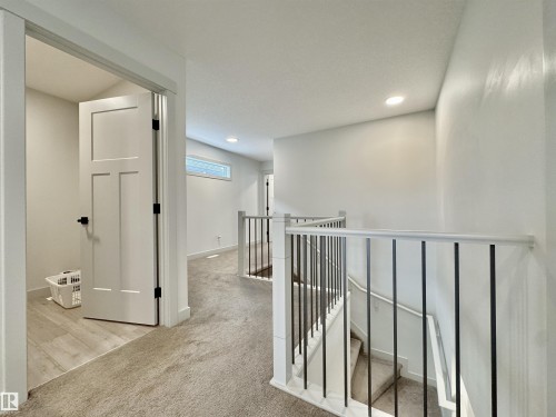 Upper-level hallway with neutral carpeting, white walls, and recessed lighting - 33 Sumac Close, Fort Saskatchewan, AB 