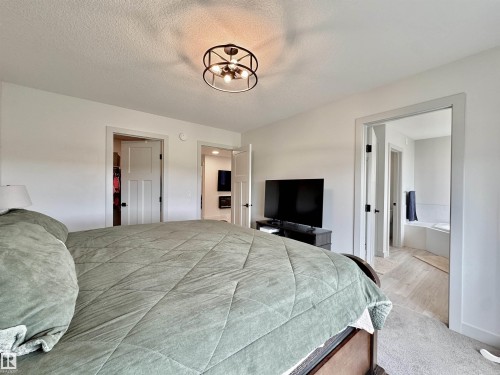 Bedroom featuring white walls and a contemporary black metal chandelier with exposed bulbs - 33 Sumac Close, Fort Saskatchewan, AB 