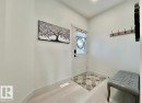 Foyer featuring light-toned wood-finish flooring, white trim, a white entry door with decorative glass, and a flush-mount ceiling light - 33 Sumac Close, Fort Saskatchewan, AB 
