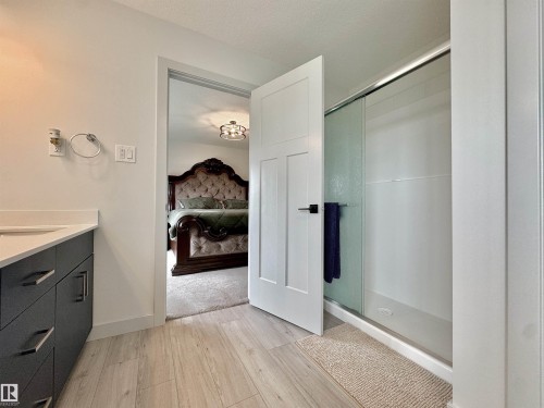 Bathroom with wood-finish flooring, a contemporary vanity with a light-toned countertop, and a glass-enclosed shower - 33 Sumac Close, Fort Saskatchewan, AB 