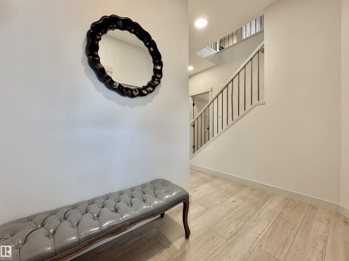 Entryway featuring light wood-finish flooring, recessed lighting, and a modern staircase with dark metal balusters - 33 Sumac Close, Fort Saskatchewan, AB 