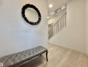 Entryway featuring light wood-finish flooring, recessed lighting, and a modern staircase with dark metal balusters - 33 Sumac Close, Fort Saskatchewan, AB 