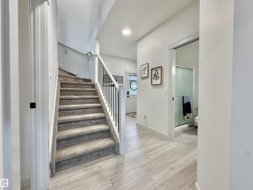 Carpeted staircase with black iron balusters and white newel posts - 33 Sumac Close, Fort Saskatchewan, AB 