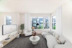 Spacious living area featuring large windows, wood-finish flooring, recessed lighting, and a neutral color palette - 